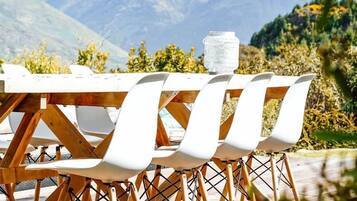 A dining table with chairs, a glass container, and a mountainous backdrop.