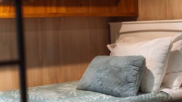 Un lit superposé avec un oreiller bleu et une couvre-lit à motifs.