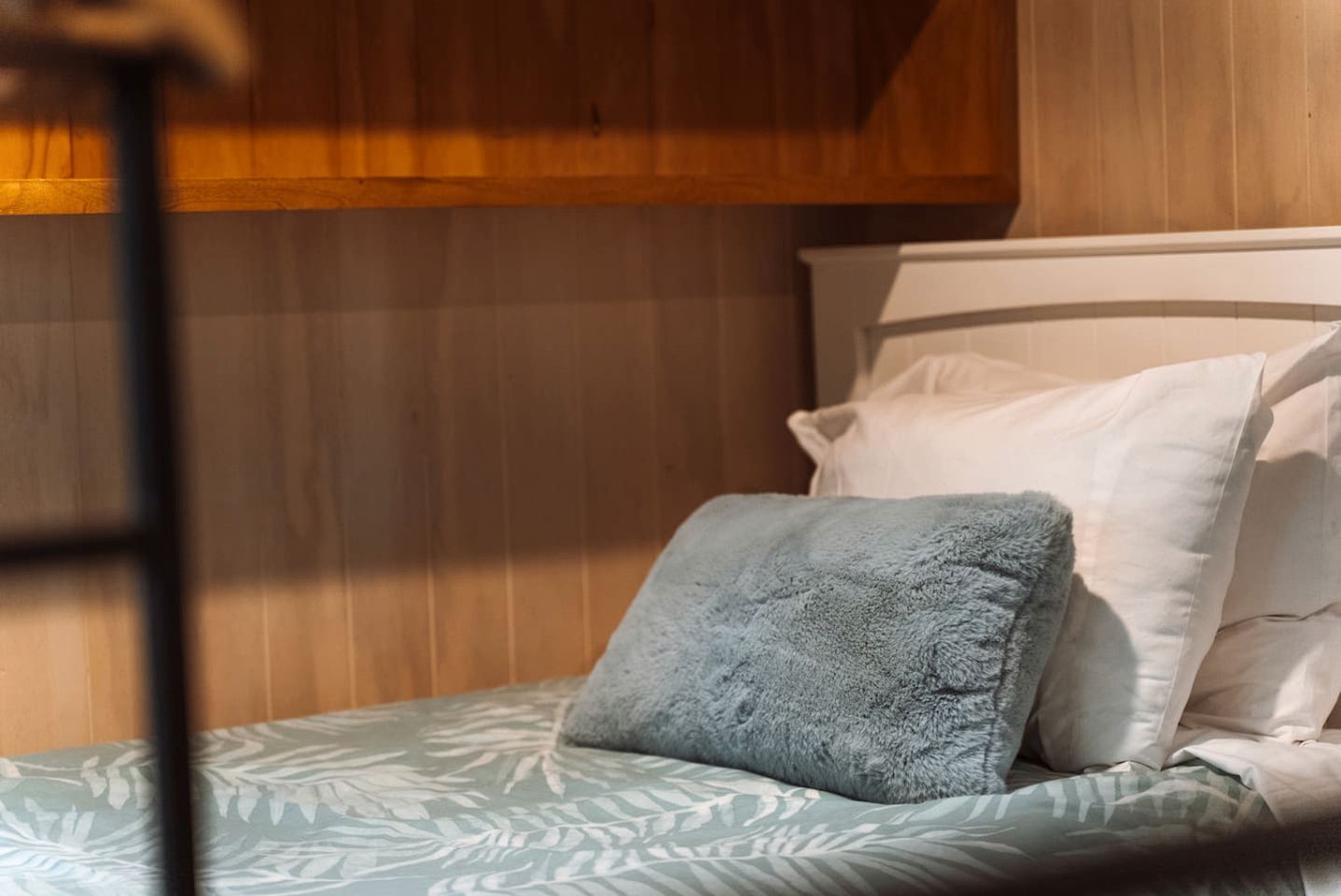 A bunk bed with a blue pillow and a patterned bedspread.