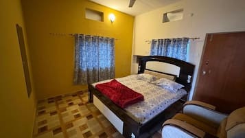 A bedroom with a bed, a ceiling fan, curtains, and a wardrobe.