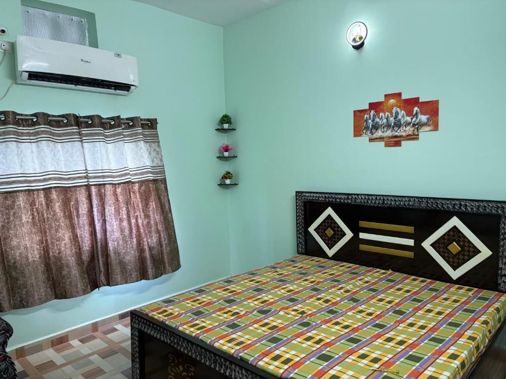 A bedroom with a bed, an air conditioner, a curtain, and a wall-mounted shelf with decorative items.