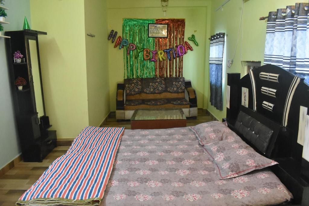 A room with a bed, a sofa, a small table, and a decorative birthday banner.