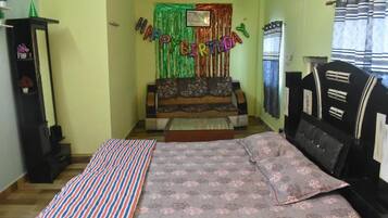 A room with a bed, a sofa, a small table, and a decorative birthday banner.