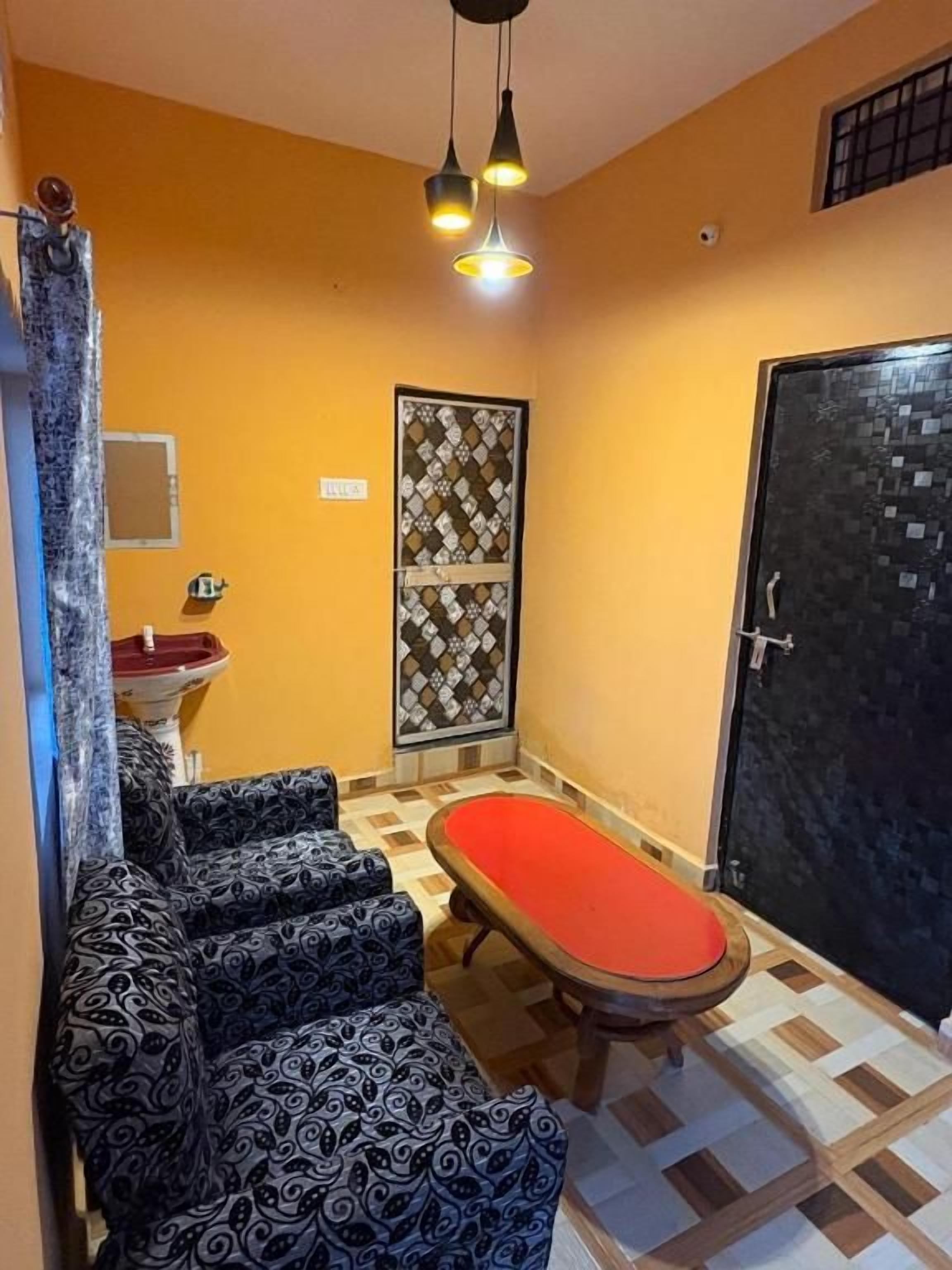 A small bathroom with a bathtub, a sink, patterned sofas, and a patterned door.