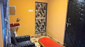 A small bathroom with a bathtub, a sink, patterned sofas, and a patterned door.