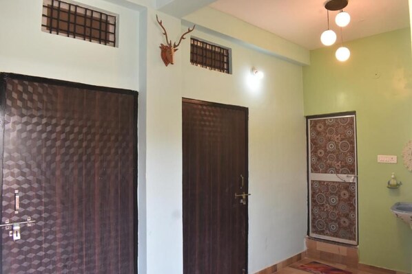 A room with two doors, one with a geometric pattern and the other plain. There is a wall-mounted deer head decoration and a patterned wall panel.