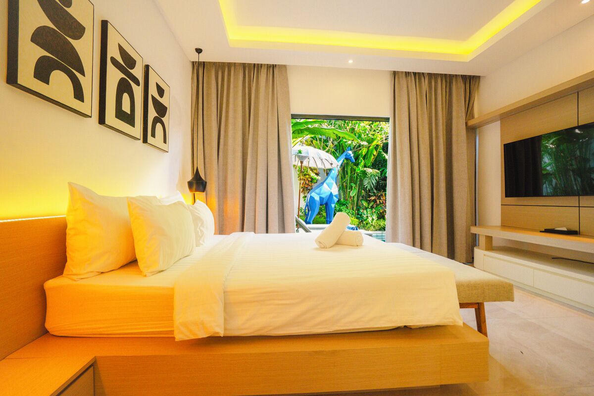 Quarto de hotel moderno com cama, televisão e vista para o verde lá fora.