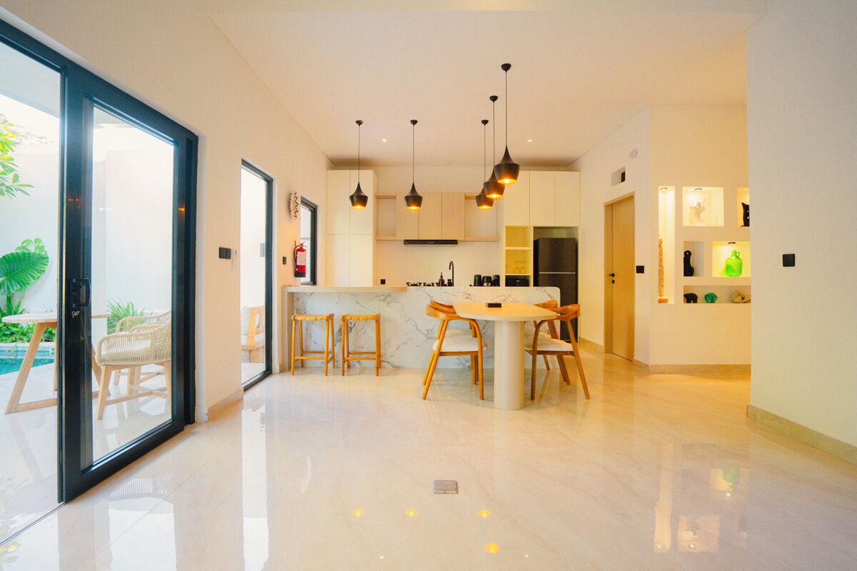 Uma cozinha moderna com ilha central, iluminação pendente e vista para o exterior.