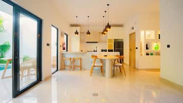 Uma cozinha moderna com ilha central, iluminação pendente e vista para o exterior.