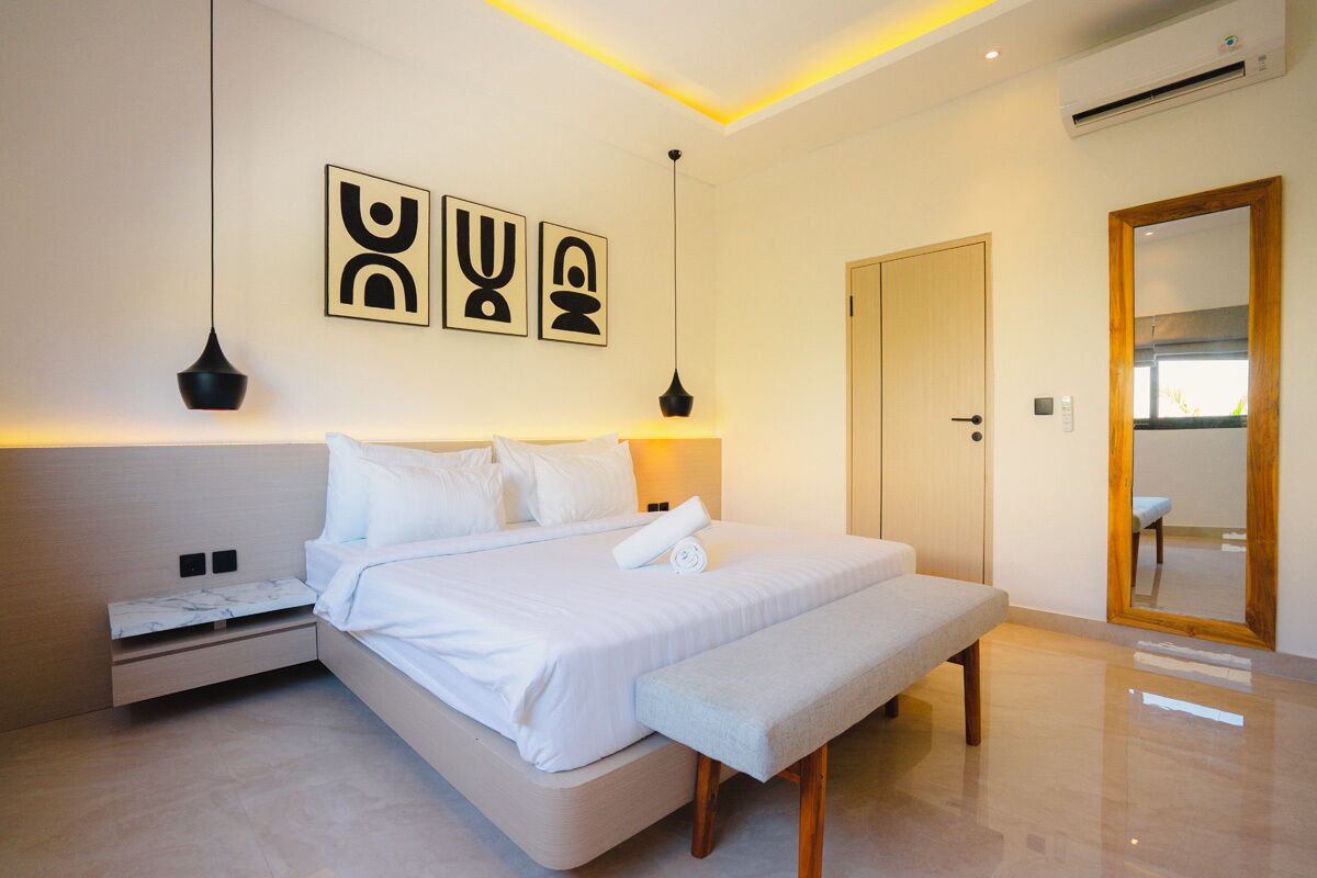 A modern bedroom with a bed, bedside tables, a bench, and wall art.