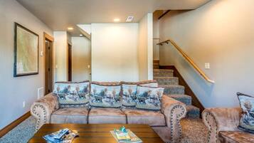 A living room with a sofa set, a coffee table, and a staircase.