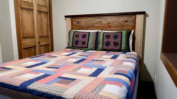 A bed with a wooden headboard and a colorful quilt.