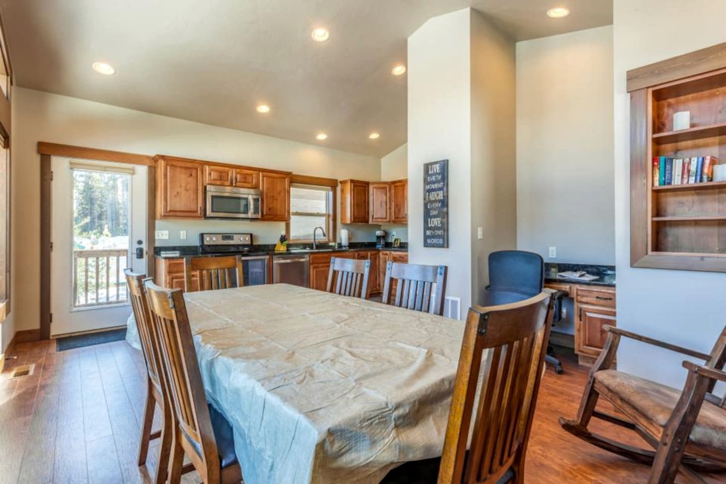A spacious kitchen with wooden cabinets, a dining table, and chairs.