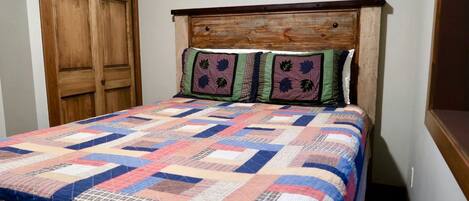 Una cama con cabecera de madera y colcha colorida.