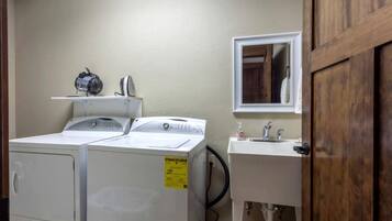 A laundry room with two washing machines, a sink, and a mirror.