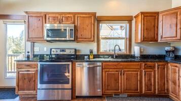 A kitchen with wooden cabinets, stainless steel appliances, a window, and a view of the outdoors.