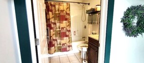 Un baño con cortina de ducha, inodoro, lavabo y toallero.