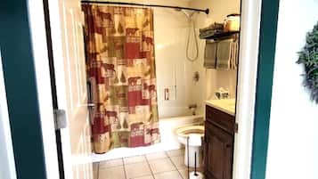 A bathroom with a shower curtain, toilet, sink, and a towel rack.