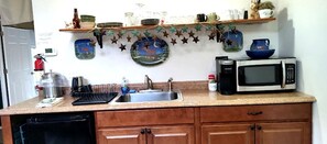 A kitchen with a microwave, sink, and wooden cabinets.