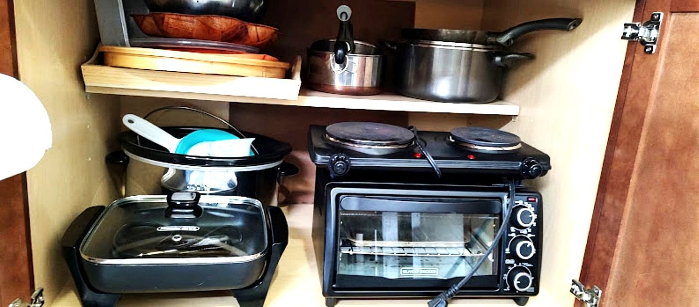 A compact kitchen with a stove, a toaster oven, a pot, and a pan.