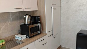 A kitchen with white cabinets, a microwave, a kettle, and a toaster.