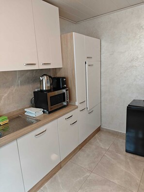 Eine Küche mit weißen Schränken, einer Mikrowelle, einem Wasserkocher und einem Toaster.