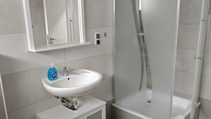 A modern bathroom with a white sink, mirror, and shower enclosure.