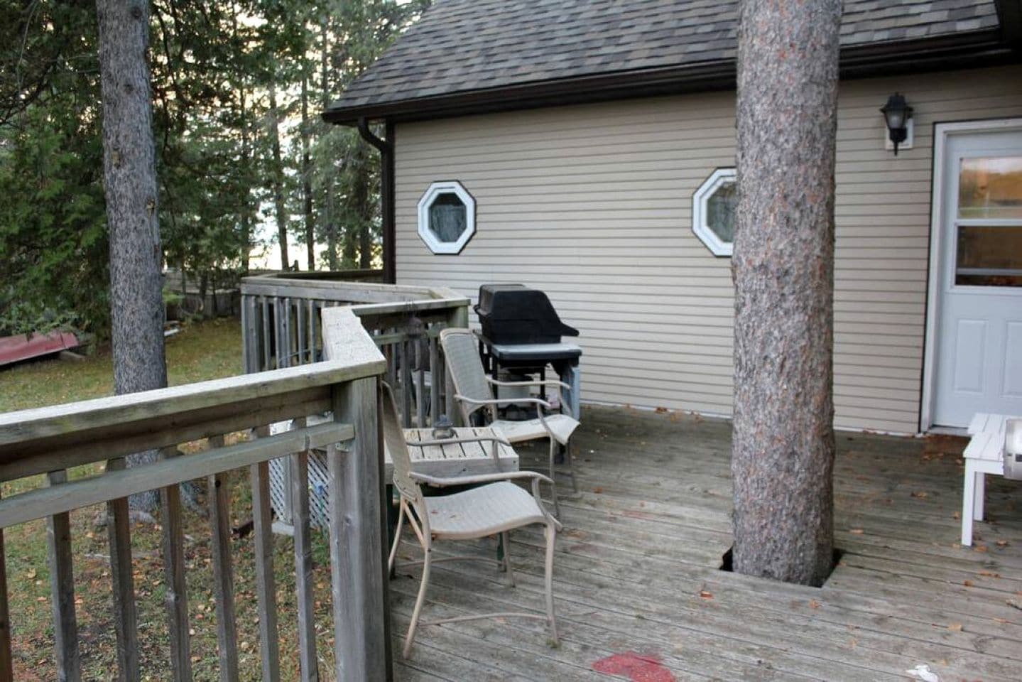 A deck with outdoor furniture, a grill, and a house with a garage door.