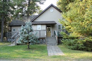 A two-story house with a front porch, a small staircase, and a tree in the yard. - Spacious Family Cottage with Stunning Sunset Views on Sturgeon Lake, Near Bobcaygeon, Ontario (Kawartha Lakes)
