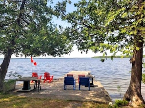 A lakeside deck with outdoor seating and a flag.