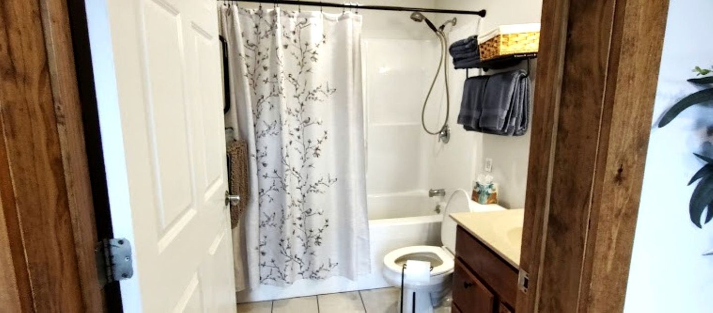 Une salle de bain avec un rideau de douche, des toilettes, une baignoire et un lavabo.