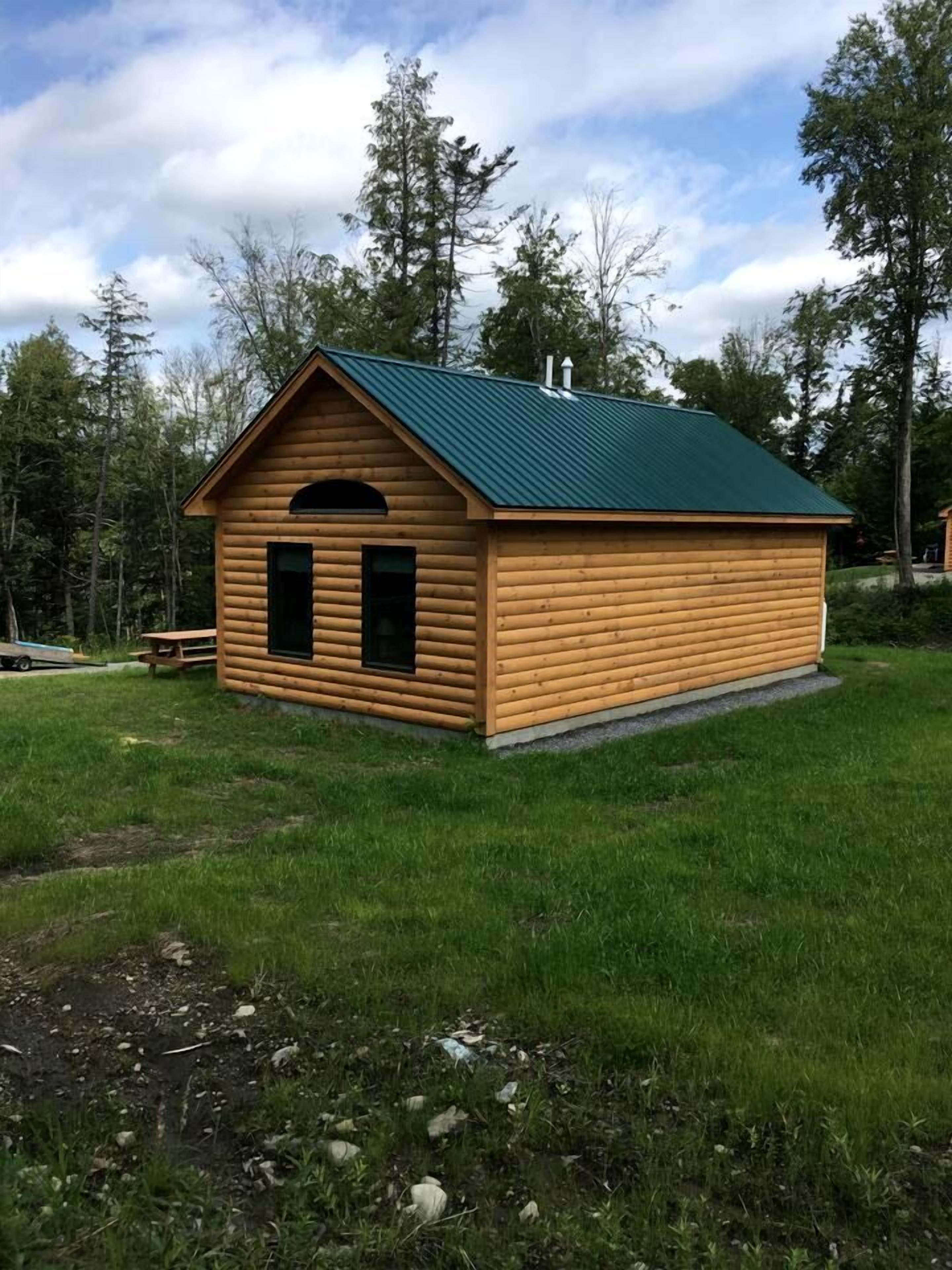 A small wooden cabin with a green roof, a single door, and a small window.