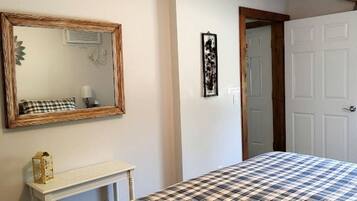 A bedroom with a bed, a mirror, a small table, and a door.