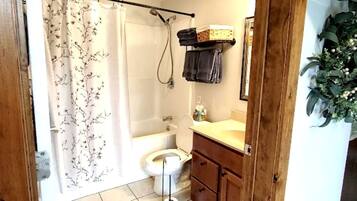 A bathroom with a shower curtain, a toilet, a sink, and a mirror.