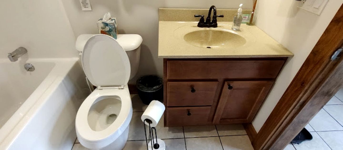 A bathroom with a toilet, sink, and wooden cabinet.