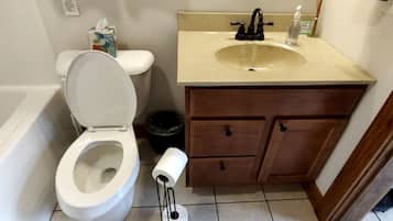 A bathroom with a toilet, sink, and wooden cabinet.