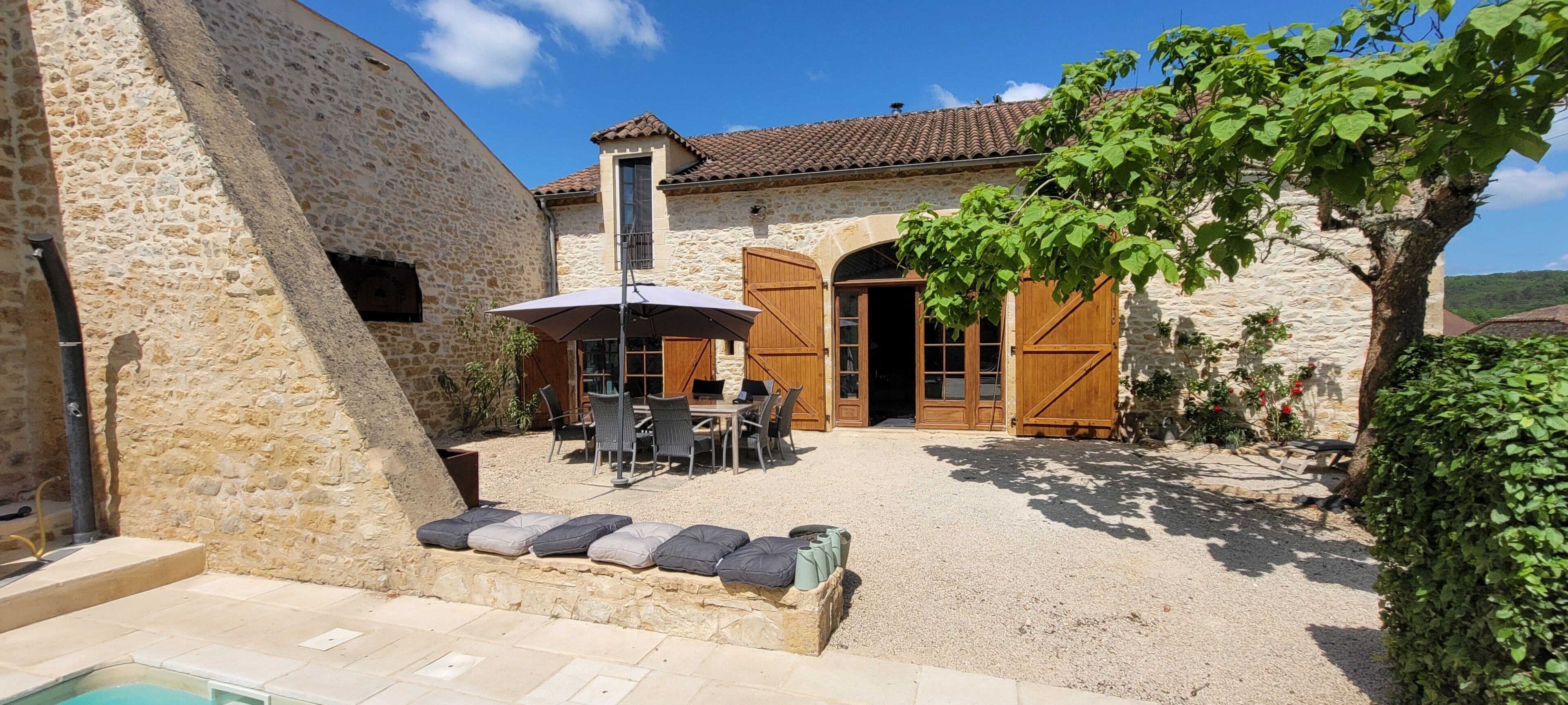 A stone building with a patio, outdoor seating, and a pool.