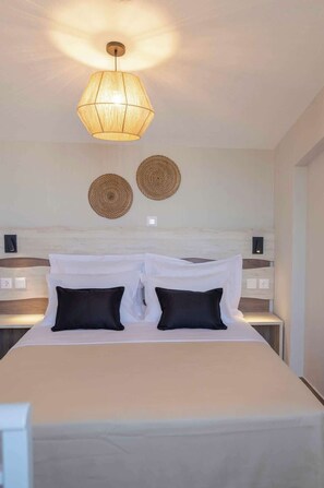 Ein modernes Hotelzimmer mit einem großen Bett, einer Hängelampe und zwei Wanddekorationen.