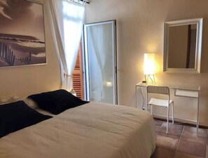 Ein Schlafzimmer mit Bett, Schreibtisch, Stuhl, Spiegel und einem Bild an der Wand.