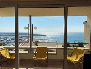 Ein Balkon mit gelben Stühlen und Blick auf das Meer, der Himmel ist klar.