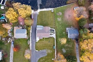 An aerial view of a residential area with three houses, a road, and a body of water. - Spacious Lakefront Cottage with Private Boat Launch on Chemong Lake, Near Peterborough, Ontario (Harcourt)