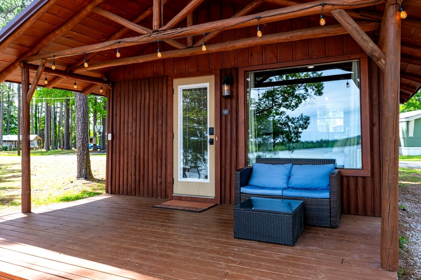 A wooden cabin with a porch, a sofa, and a table.