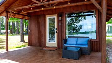 A wooden cabin with a porch, a sofa, and a table.