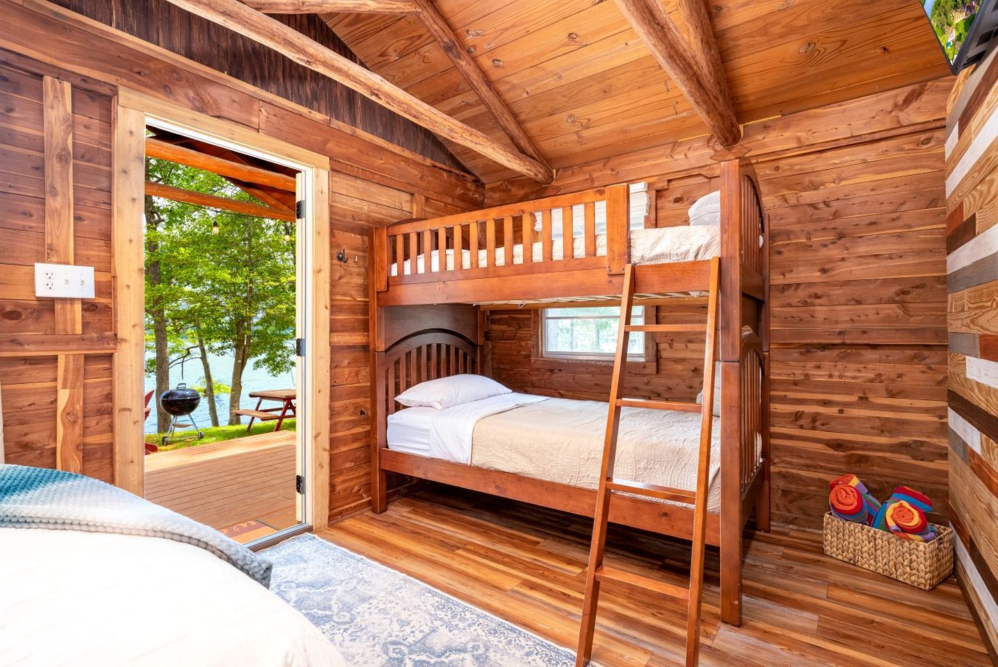 Uma cabana de madeira com beliche, vista para o exterior e uma mesa de piquenique.
