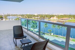Ein Balkon mit Korbstühlen und Blick auf Stadt und Wasser.