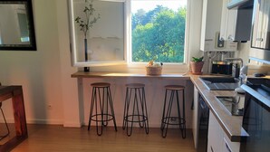 Une cuisine moderne avec une fenêtre, des tabourets et un lave-vaisselle.