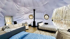Ein gemütliches Interieur mit einer Couch, einem Bett, einem runden Tisch und einer zeltartigen Konstruktion.