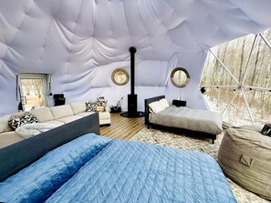 A cozy interior with a sofa, a bed, a round table, and a tent-like structure.