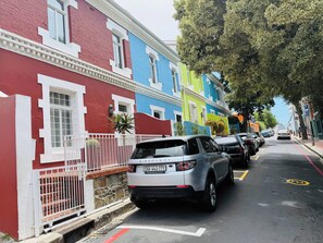 Eine Straße mit bunten Häusern, parkenden Autos und freier Fahrt.