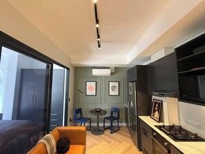Eine moderne Küche mit Gasherd, Kühlschrank und Essbereich mit zwei Stühlen und einem kleinen Tisch.